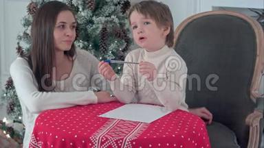 年轻的母亲帮助她挣扎的儿子给圣诞老人写一封信